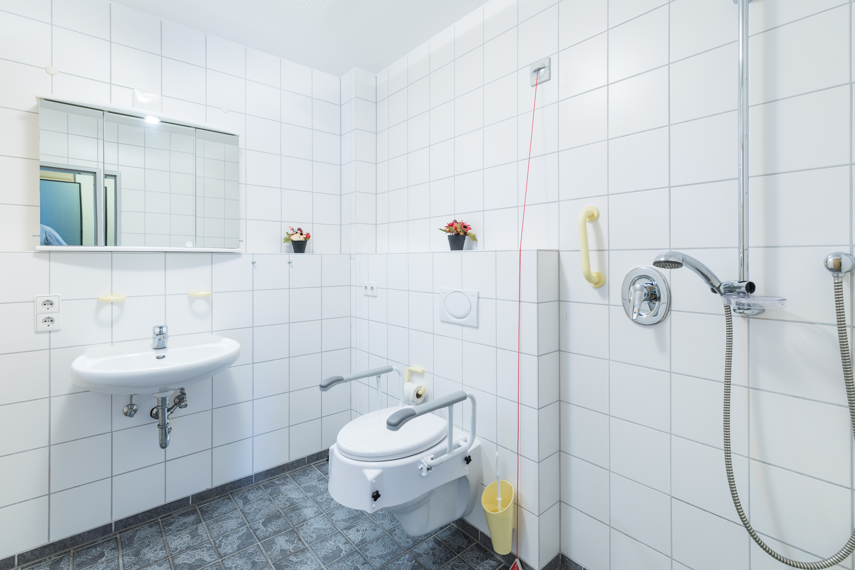 Barrierefreies Pflegebad mit bodengleicher Dusche und Haltegriffen