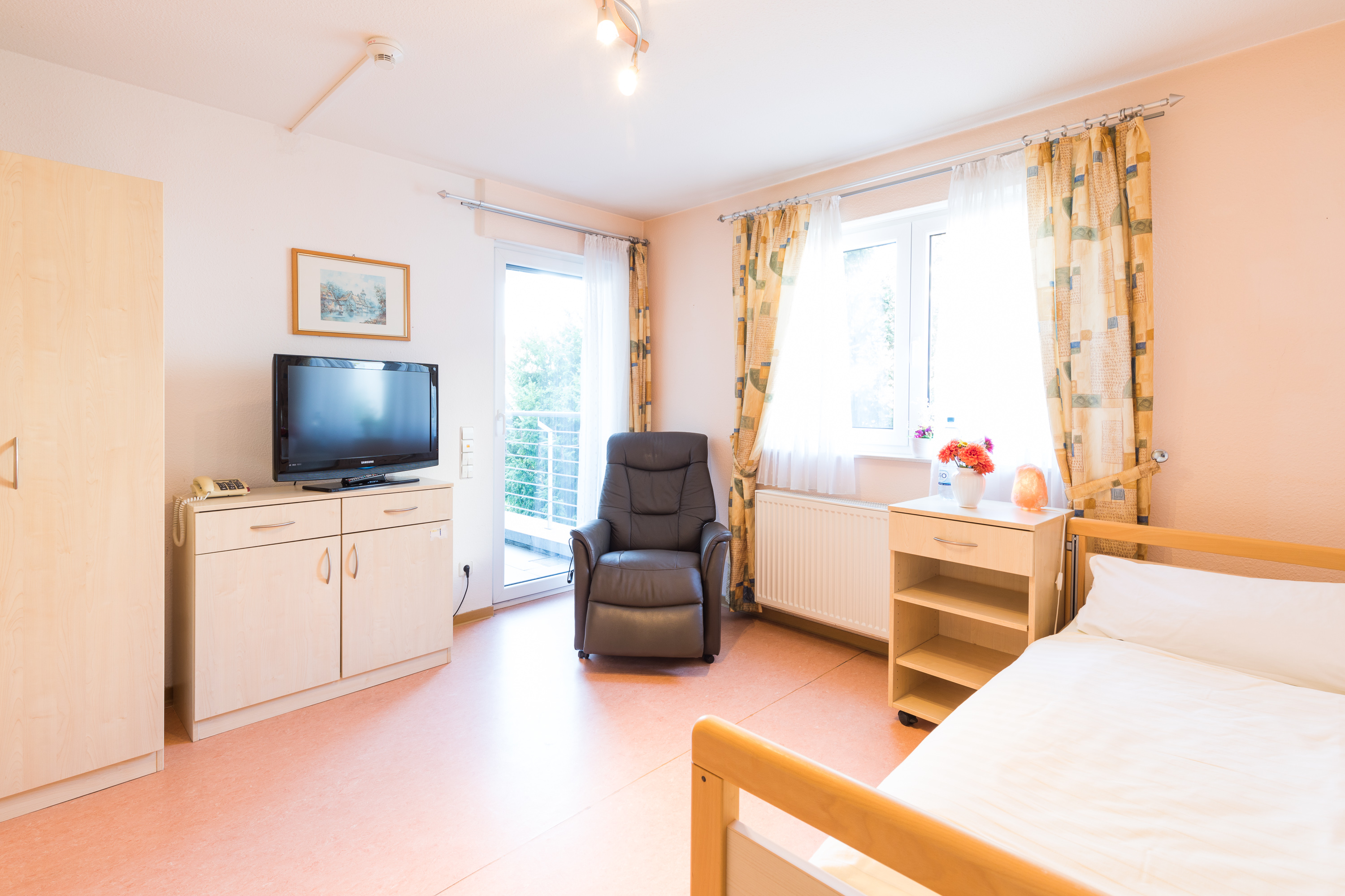 Pflegezimmer mit Pflegebett, Sessel und eigenem Fernseher